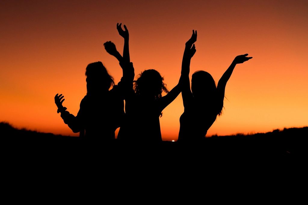 Silhouettes de personnes qui célèbrent au coucher du soleil